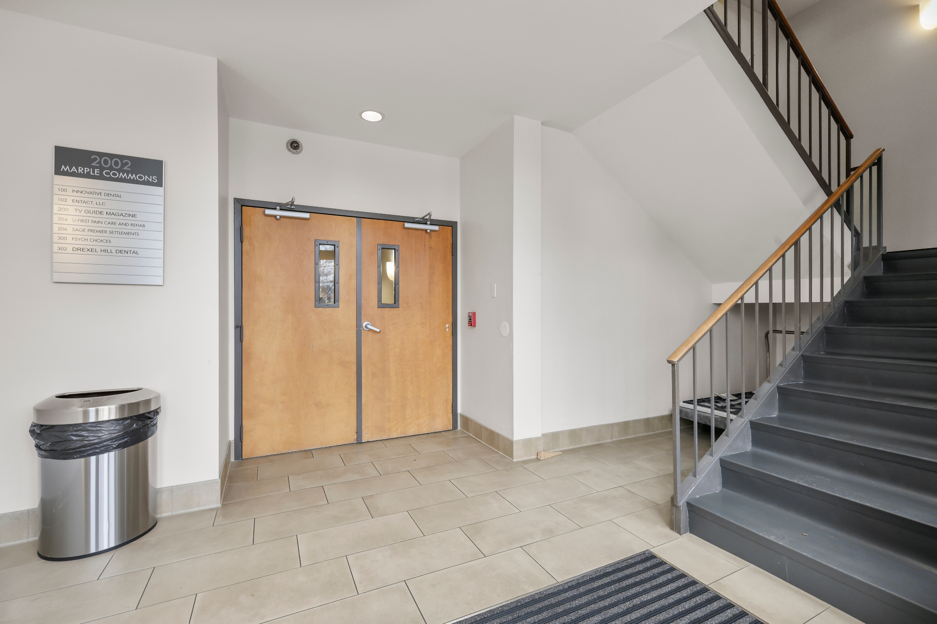 Office building lobby with directory signage, stair, and new tile flooring