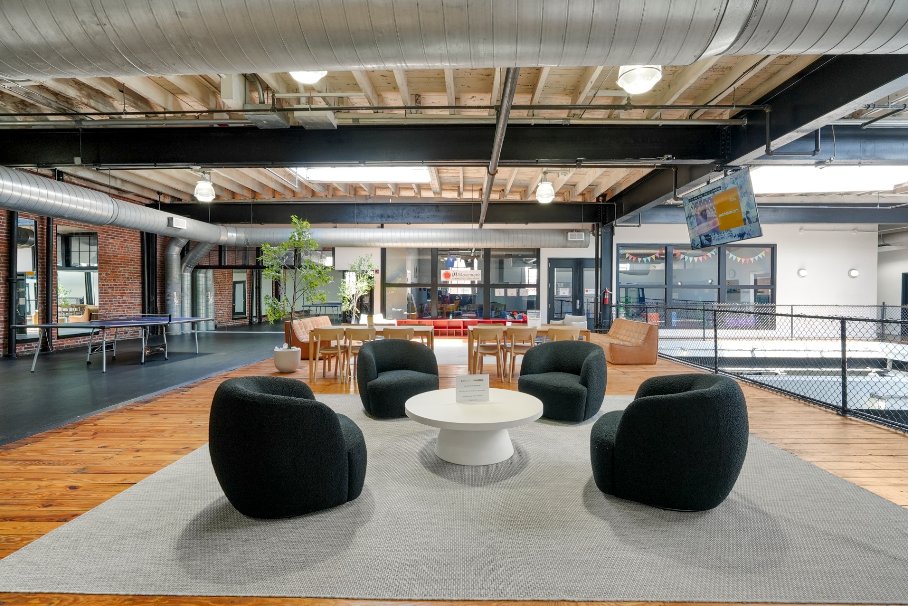 Community lounge with bouclé chairs over reclaimed wood decking